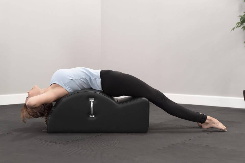 Persona izstiepjas uz East Coast Step Barrel Pilates vingrinājumam.