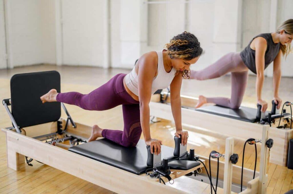 Pilates vingrinājums ar studijas reformeru un lēcienu dēli studijā.
