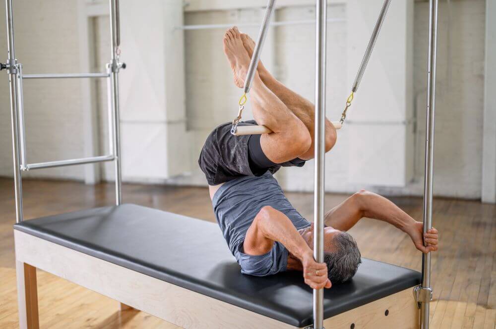 Pilates Trapeze Table demonstrācija ar lietotāju, kurš vingro uz Cadillac.