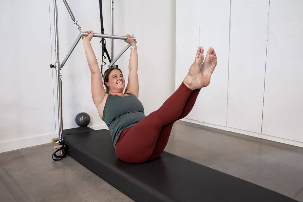 Sieviete vingro uz sienas torņa ar Pilates paklājiņa atbalstu.