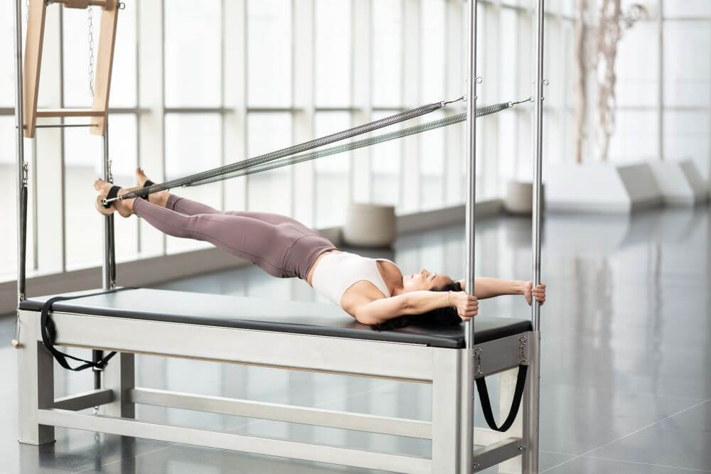 Pilates vingrinājums, izmantojot Contrology Airplane Board uz Cadillac trenažiera.