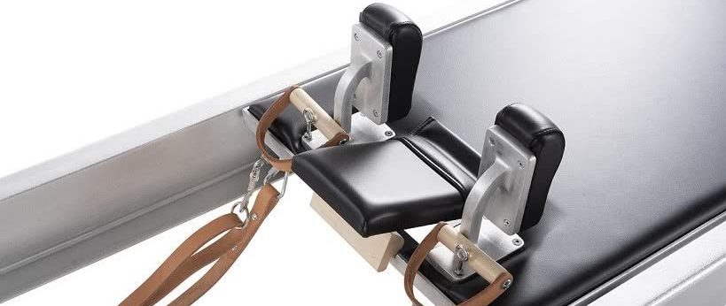 Pilates Reformer pārvietojamā platforma ar vienmērīgu kustību un melnu polsterējumu.