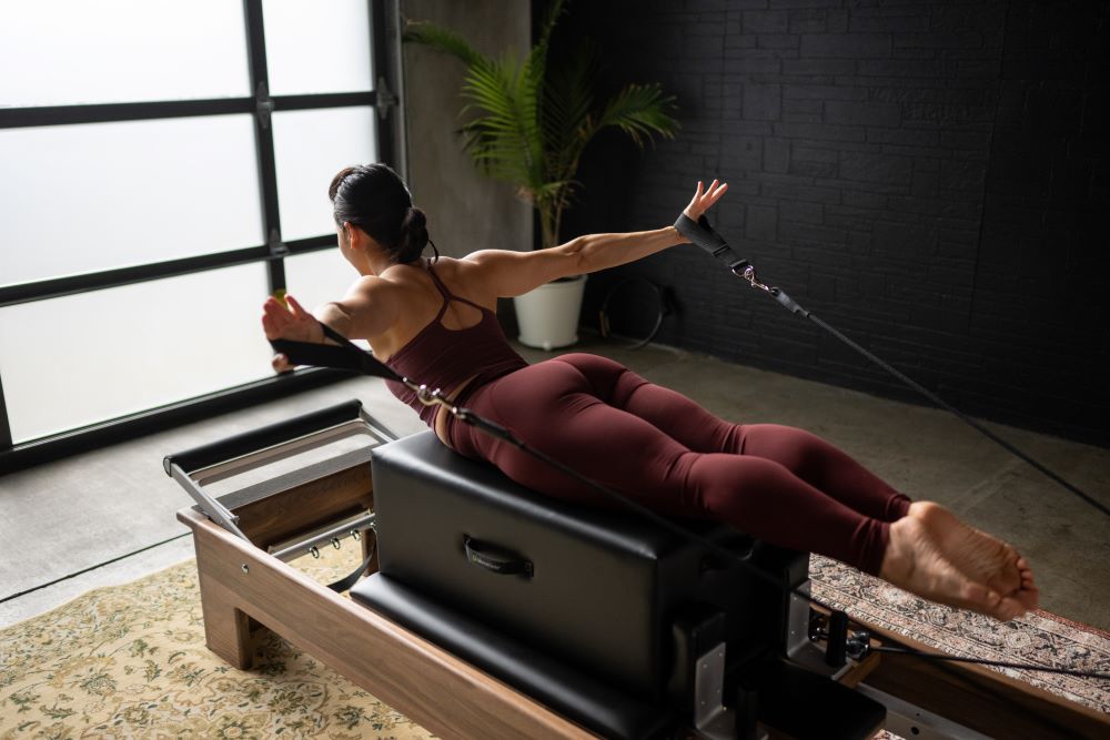 Pilates vingrinājums ar Ņujorkas sēdēšanas kasti uz reformera.