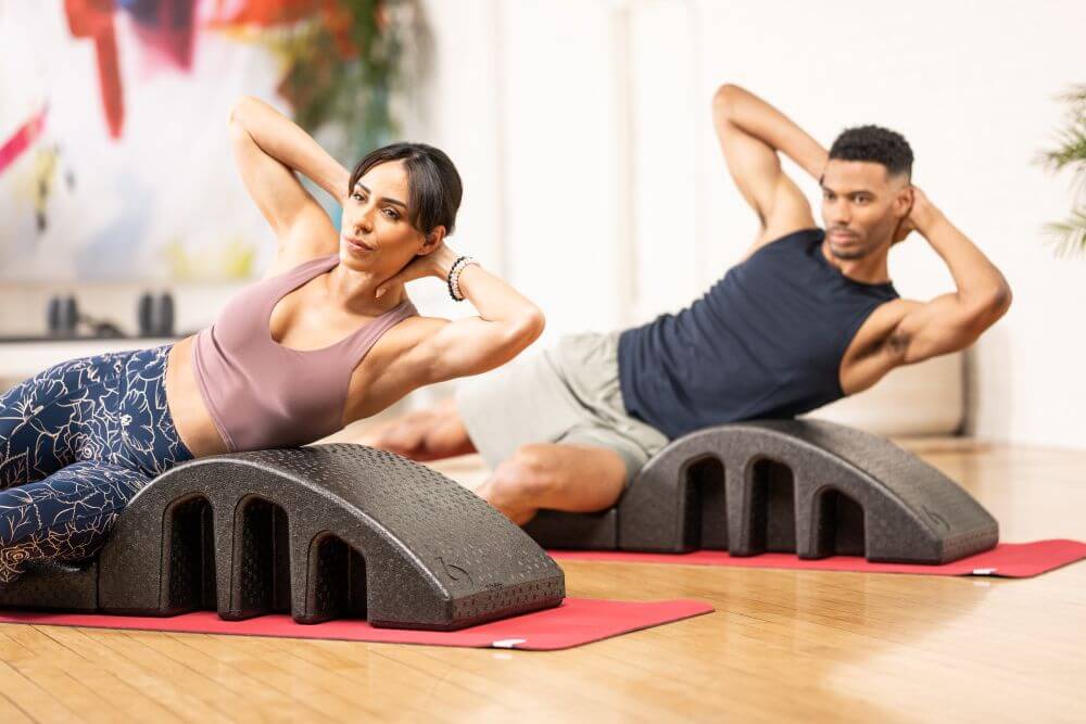 Два человека занимаются на дугах для пилатеса в студийной обстановке.