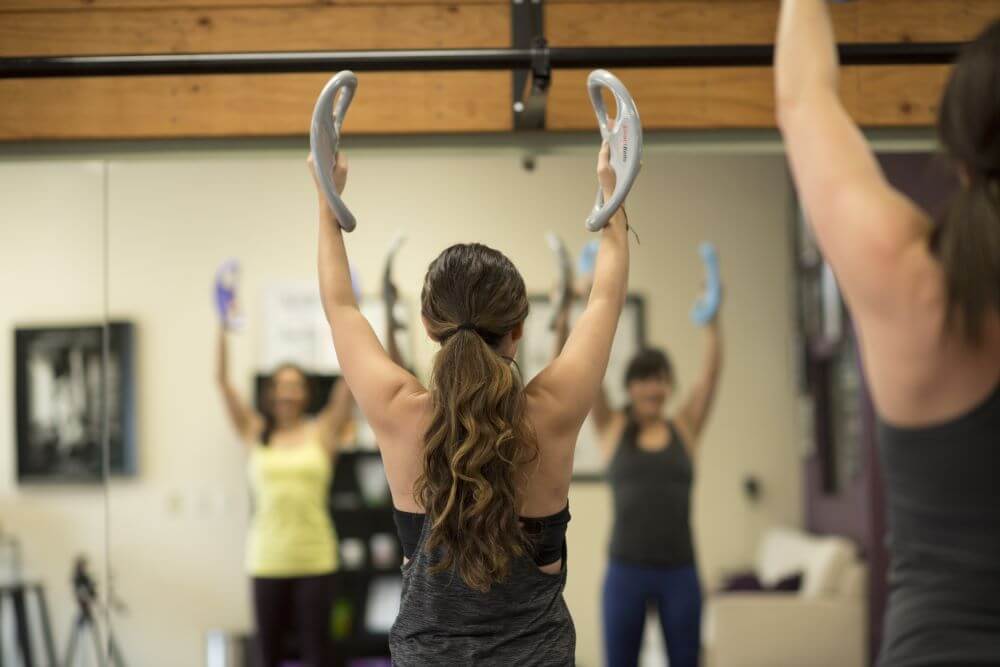 Люди используют SmartBell от Balanced Body на занятии по пилатесу.