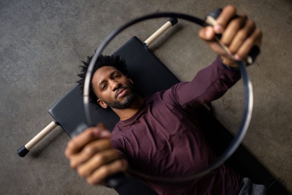 Человек использует пружинный круг Balanced Body для упражнения по пилатесу.