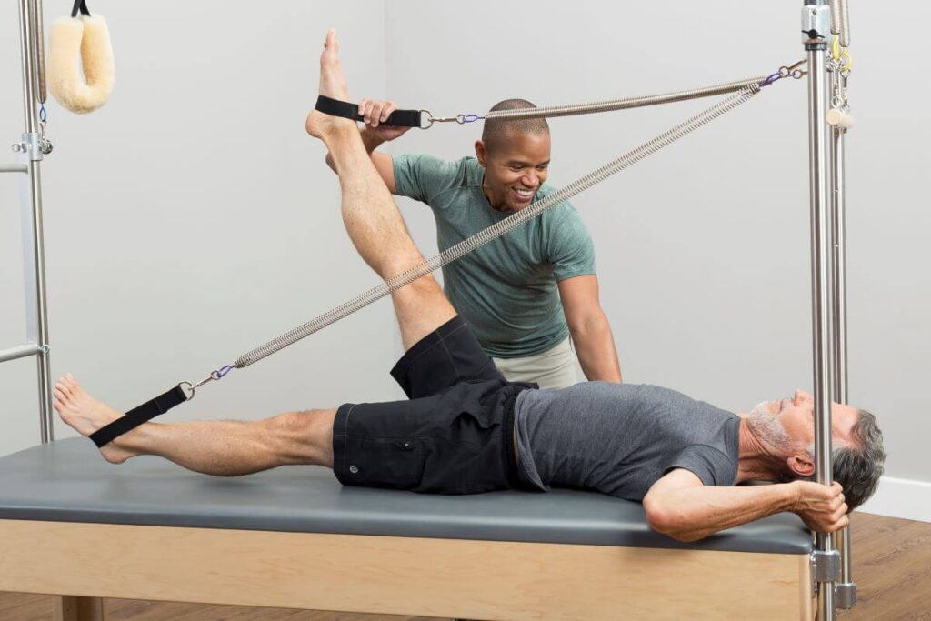 Instructor assisting client with Pilates on Trapeze Signature Springs.