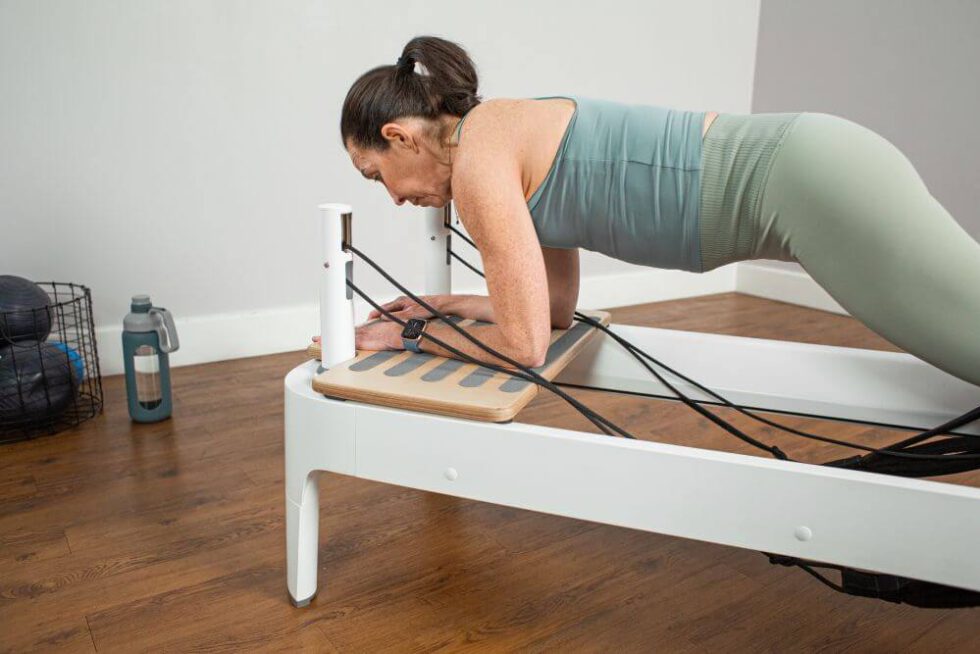 Persona izmanto Allegro 2 Head End Extended Platform uz Reformer trenažiera.