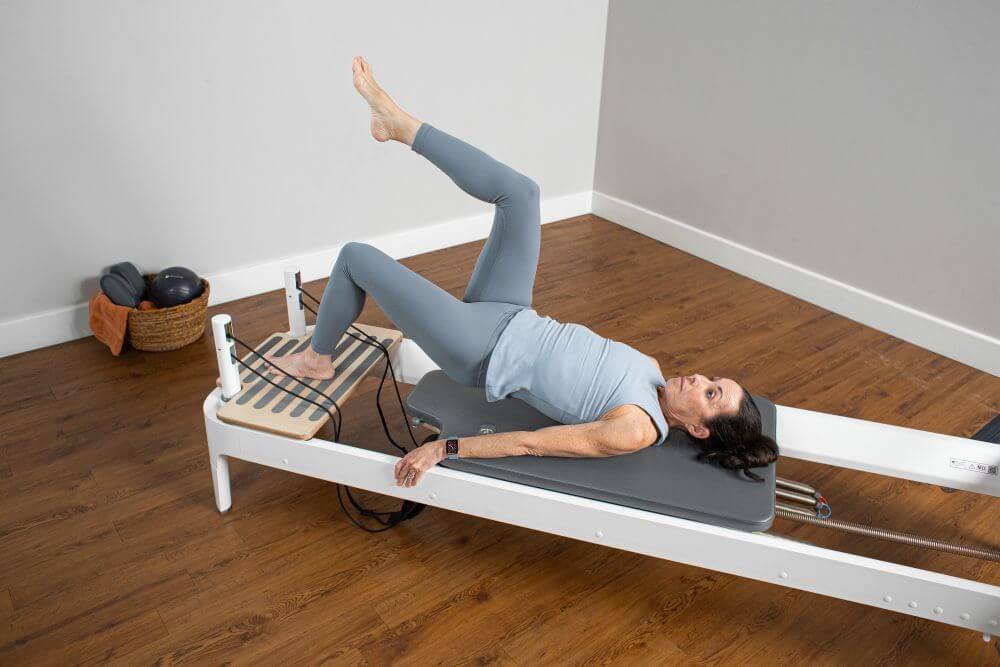 Sieviete izmanto Allegro 2 Head End Extended Platform Pilates vingrinājumiem.