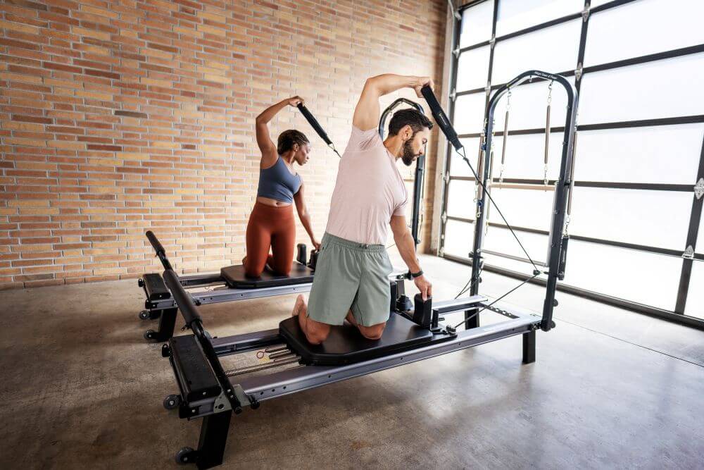 Два человека занимаются на Allegro Nextgen Reformers с башнями в студии.