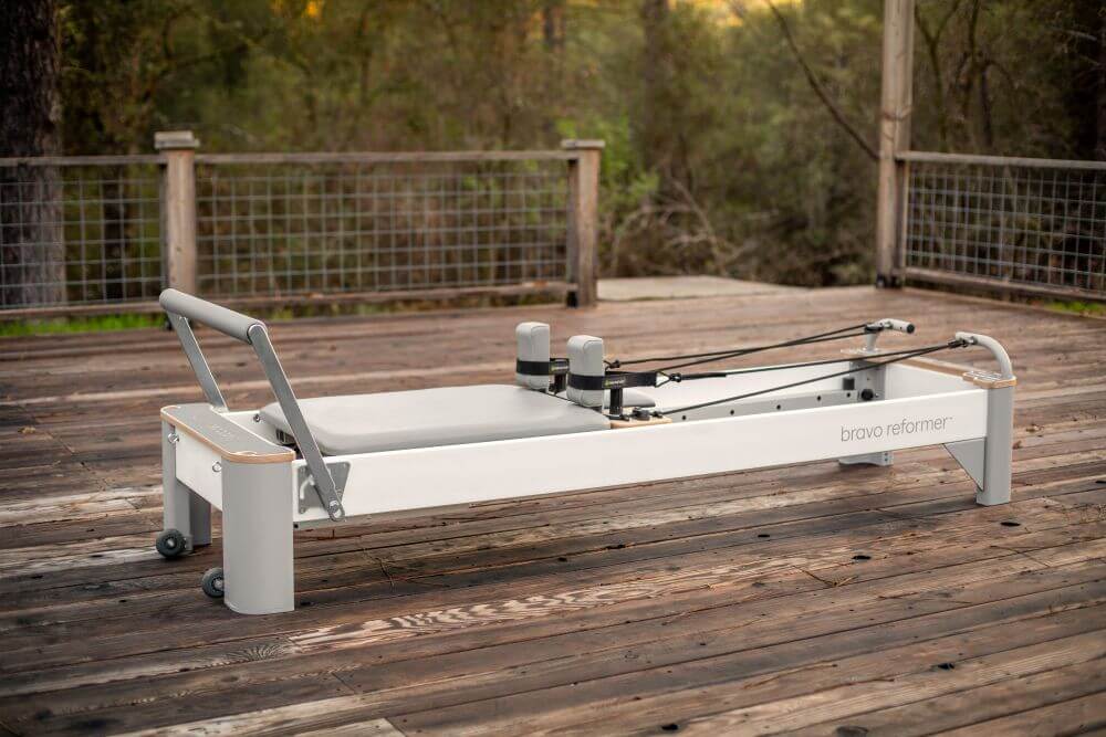 Оборудование для пилатеса Bravo Reformer на деревянной террасе, на открытом воздухе.